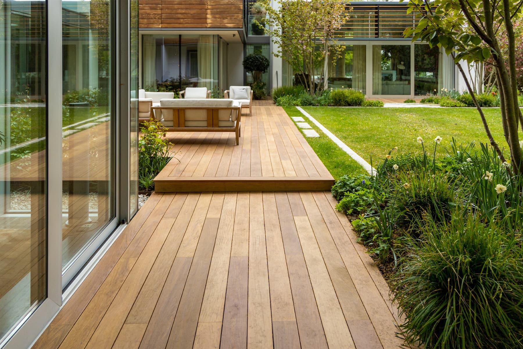 Modern wood deck with glass railings and landscaped backyard creating an open outdoor space